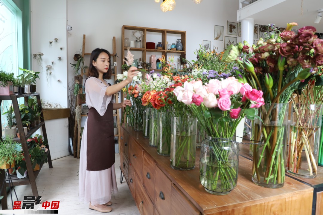 王黎媛是一名河南姑娘，在昆明念完大學(xué)后，就再也舍不下春城的藍天陽光、青山碧水，更舍不下這里的四時繁花，于是就干脆留了下來，成了一名媒體人。2017年的時候又毅然辭去工作，創(chuàng)業(yè)開起了花店，成了都市里的一名“花房姑娘”。圖為王黎媛在自己的花店中整理鮮花。新華網(wǎng) 周亞平/攝 念新洪/文